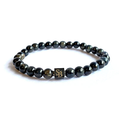 Een donkerblauwe kralenarmband met een gouden logo erop.